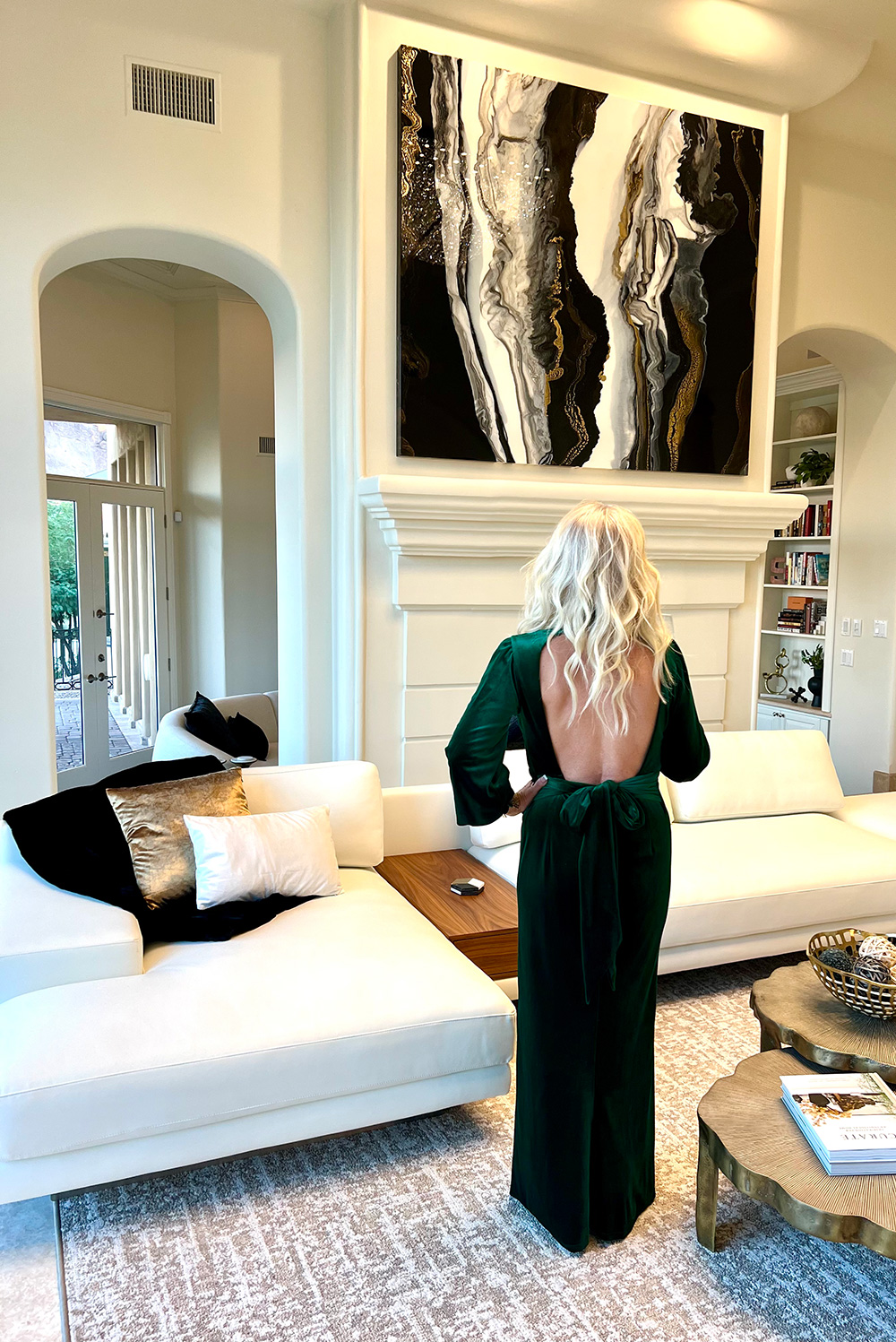 Niki Woehler admiring her art piece in a long green dress.